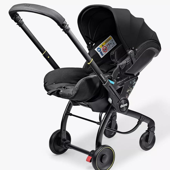 Black baby stroller with car seat attachment on a white background